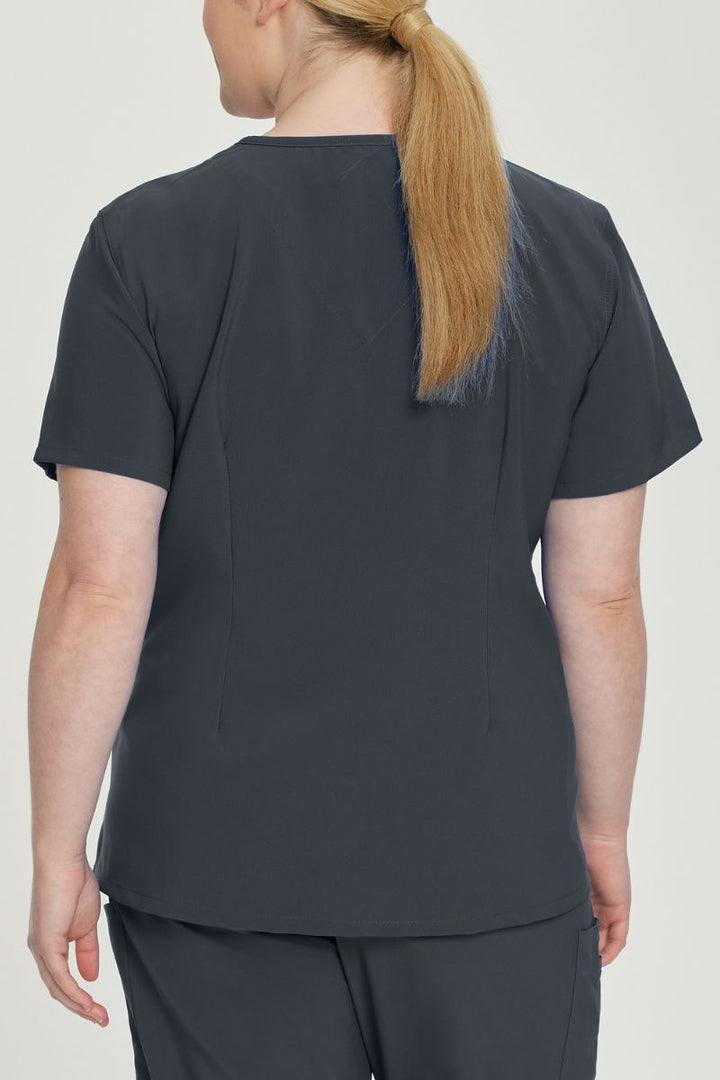 A young female Medical Assistant wearing an Urbane Performance Women's Motivate V-neck Scrub Top in Graphite size 3XL featuring a unique, 4-way stretch fabric.