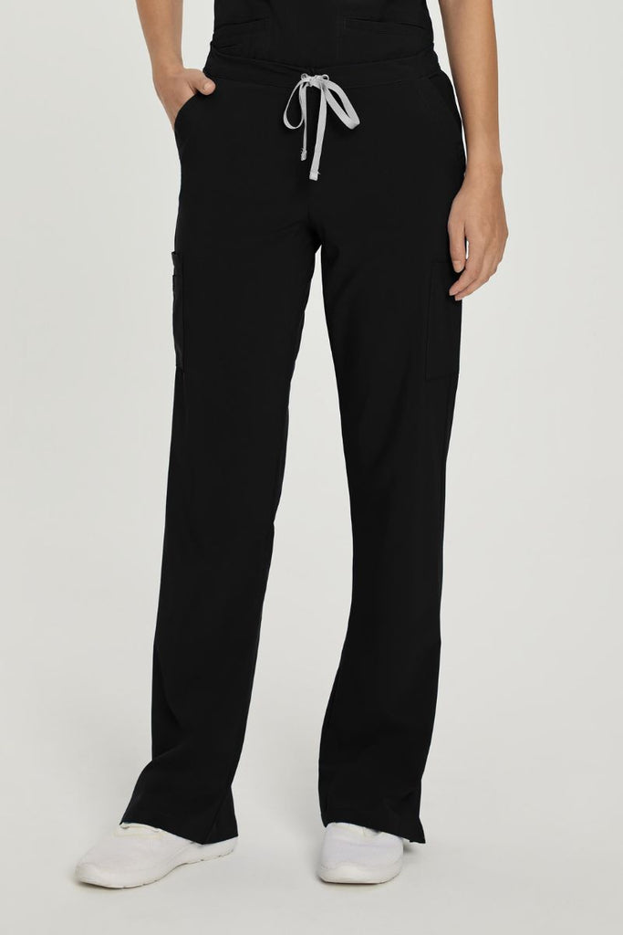 A young female Surgeon wearing a pair of the Urbane Performance Women's Endurance Cargo Scrub Pants in Black size Medium featuring a unique, fabric that fights wrinkles and fading, ensuring you maintain a professional appearance wash after wash.