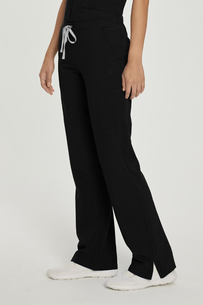 A young female Doctor wearing a pair of the Urbane Performance Women's Endurance Cargo Scrub Pants in Black size Small featuring a mid-rise design sits comfortably at your natural waist, while the drawstring closure allows for a personalized fit.
