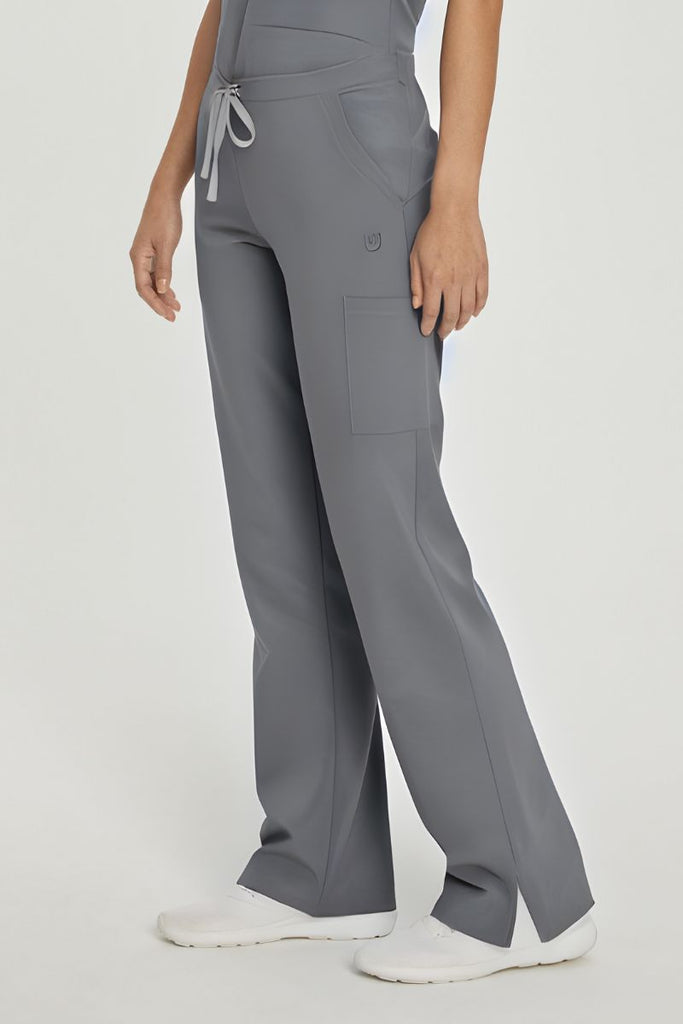 A young female Home Health Aide wearing a pair of Urbane Performance Endurance Cargo Scrub Pants in Steel Grey featuring a unique fabric that fights wrinkles and fading, ensuring you maintain a professional appearance wash after wash.