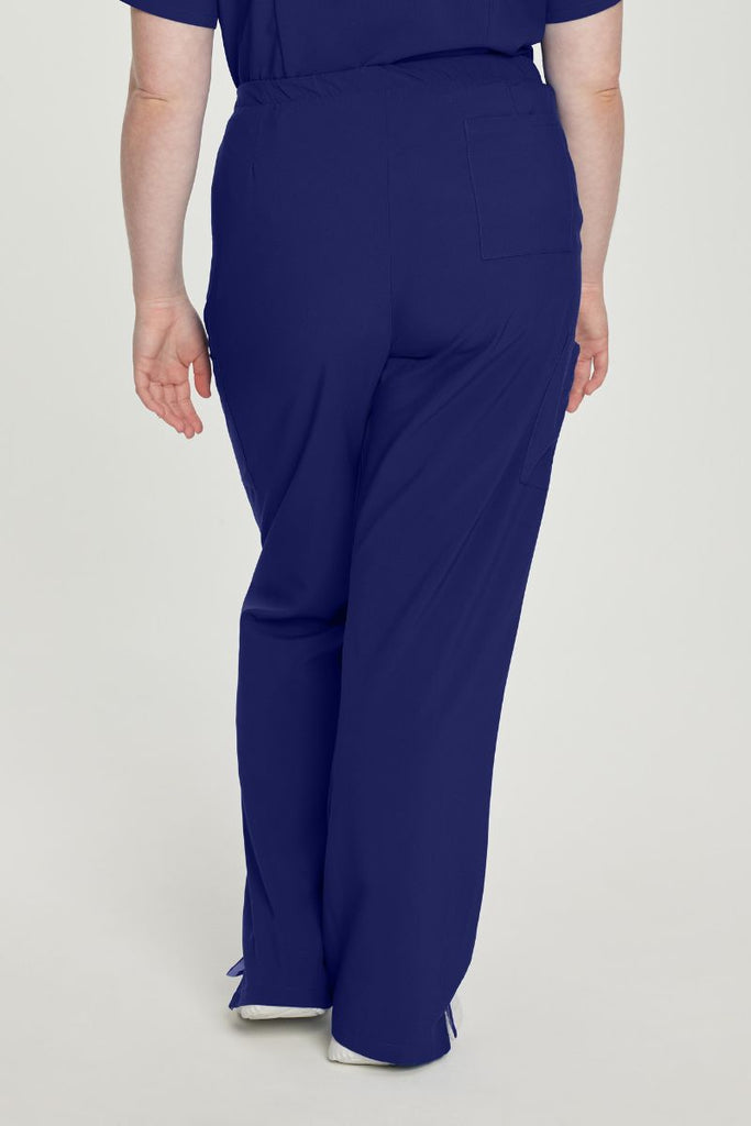 A young female Nurse Practitioner showcasing the back of the Urbane Performance Endurance Cargo Scrub Pants in True Navy size 3XL featuring one back welt pocket for additional storage space.