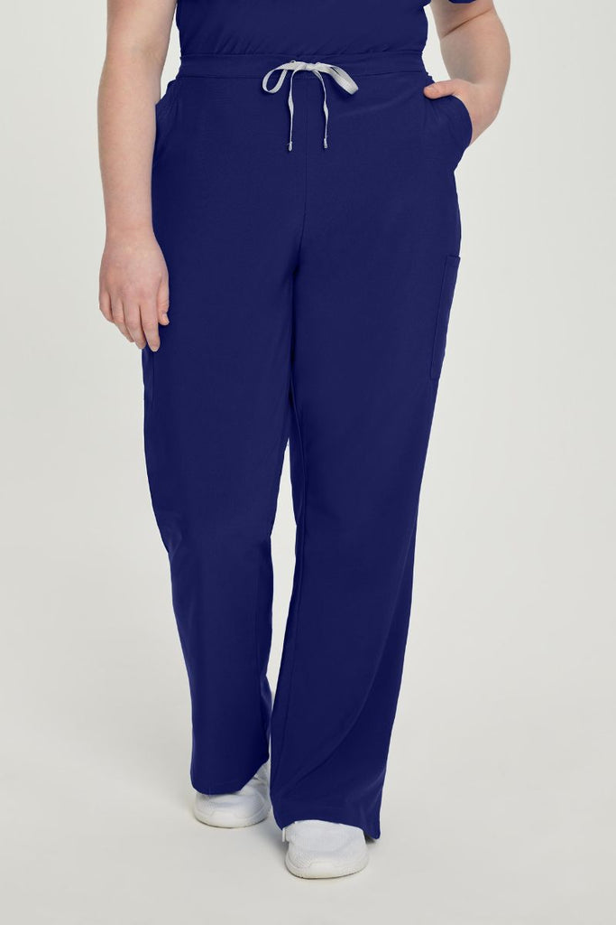 A young female nurse showcasing the front of the Urbane Performance Endurance Cargo Pants in True Navy size 4XL featuring a mid-rise construction with a drawstring closure.