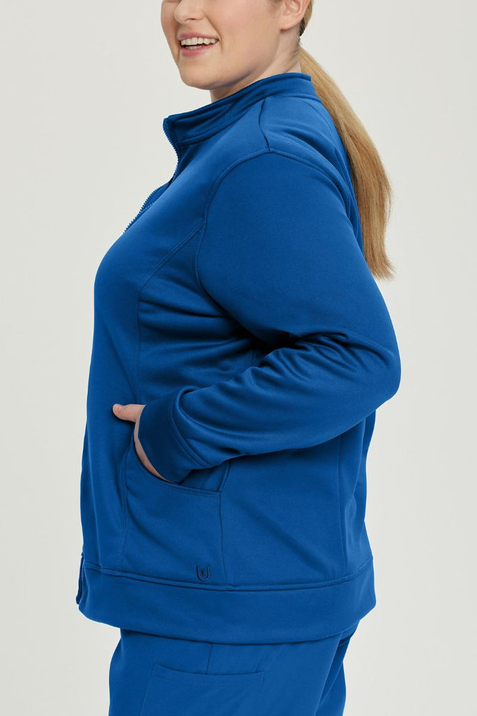 A young female Physical Therapist wearing an Urbane Performance Women's Zip-Up Scrub Jacket in True Navy size 2XL featuring stylish, princess seaming throughout.