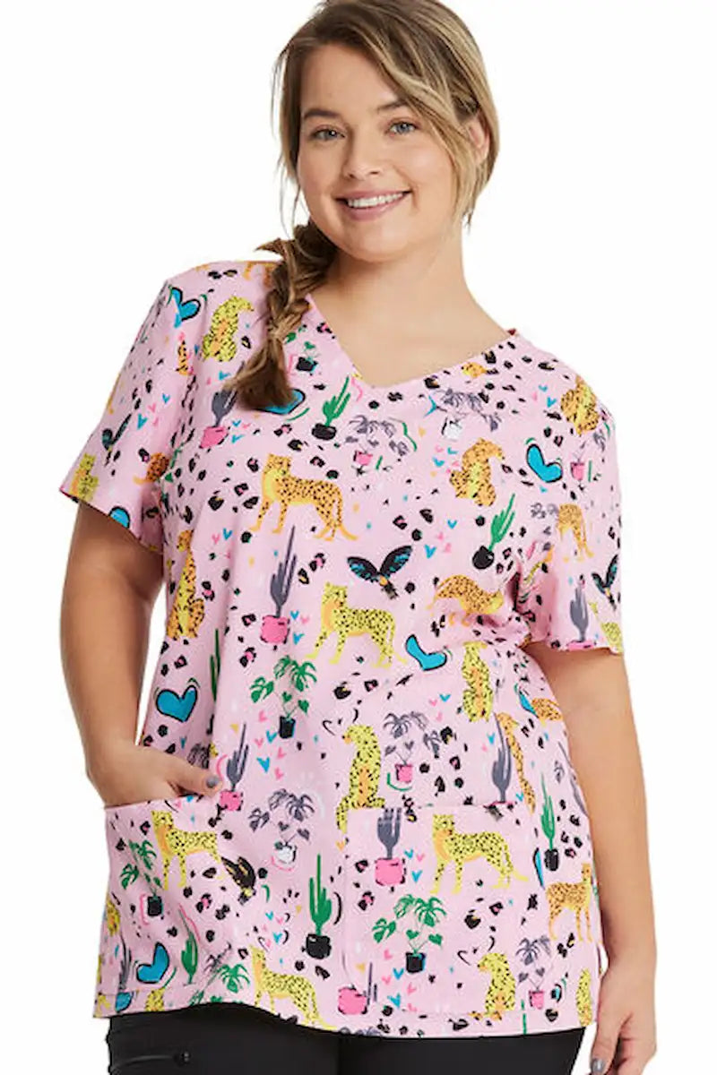 A young female Healthcare Professional wearing a HeartSoul Women's V-Neck Printed Scrub Top in Jungle of Love featuring princess seams throughout to provide a flattering fit.