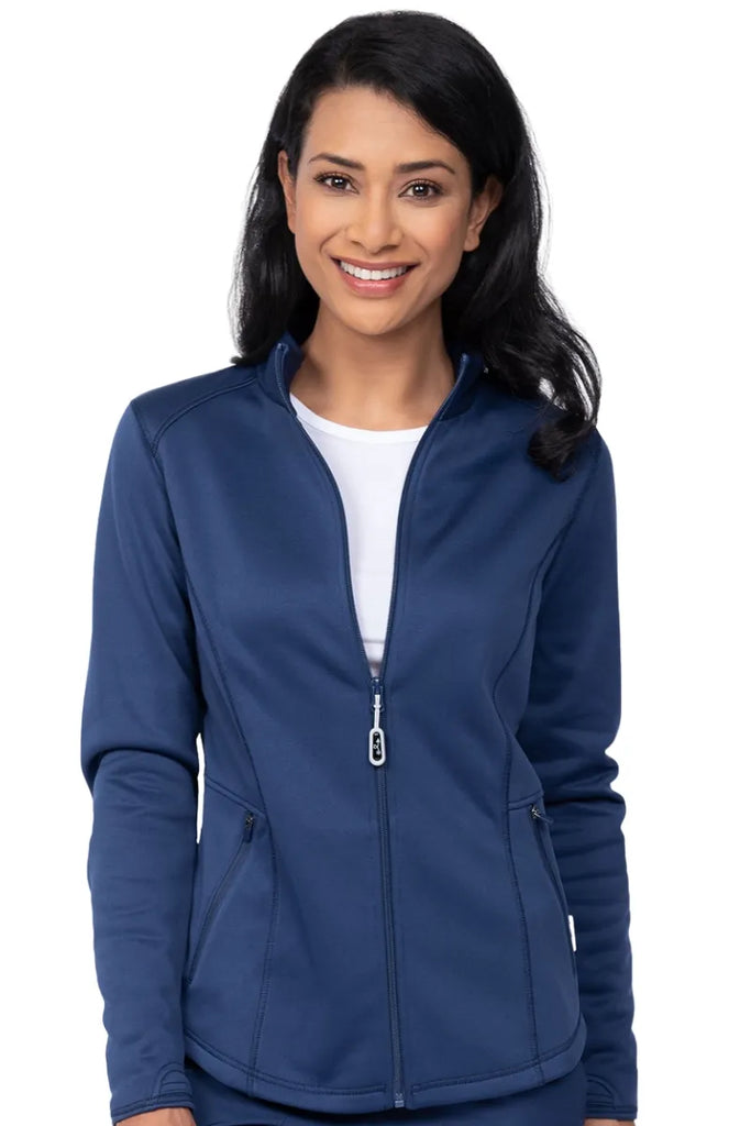 A young female medical assistant wearing an Ava Therese Women's Bonded Fleece Jacket in Navy size Medium featuring a two front zip close pockets.