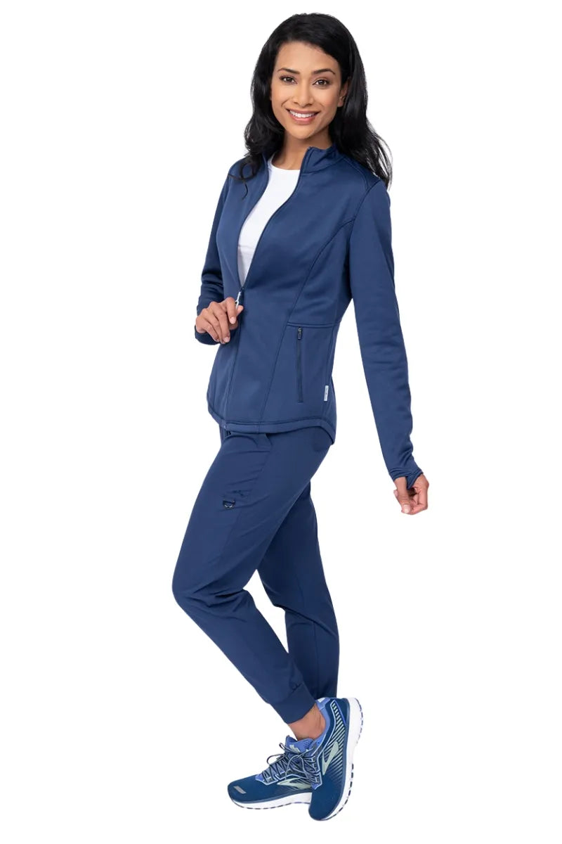 A full body image of a young female Physical Therapist wearing an Ava Therese Women's Bonded Fleece Jacket in Navy size Large featuring a soft, light fleece has an anti-static finish.