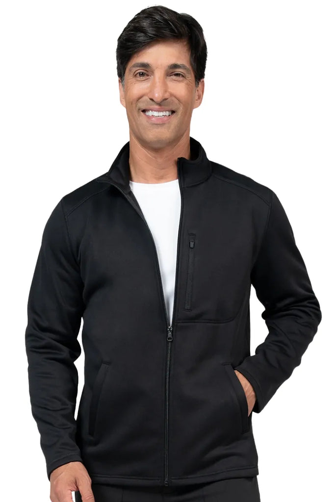 A young male Physical Therapist wearing a Brandon Men's Bonded Fleece Jacket in Black size Small featuring two front on seam pockets for all your on the job storage needs.
