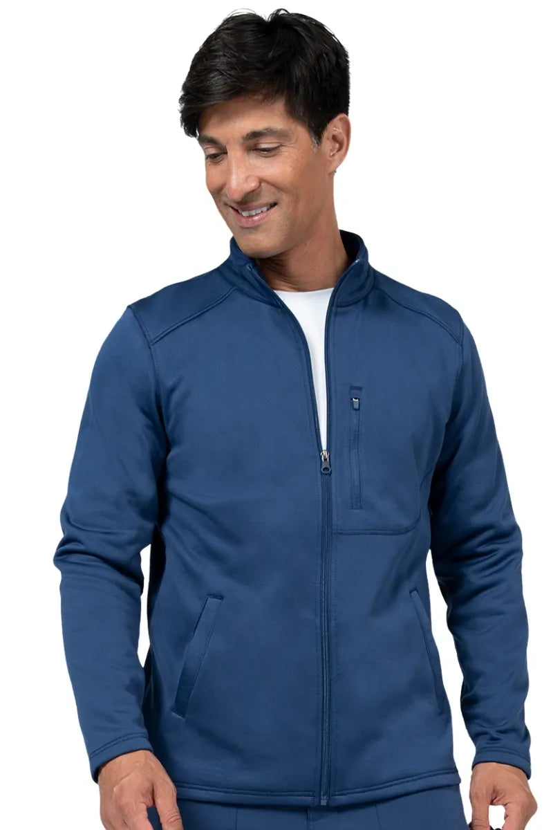 A young male nurse practitioner wearing a Brandon Men's Bonded Fleece Jacket in Navy size medium featuring two front on seam pockets for all your on the job storage needs.