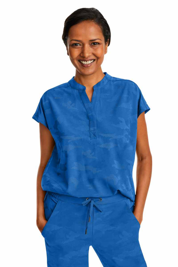 A young female Nurse Practitioner wearing a Products Purple Label Women's Journey Camo Top in Royal size Small featuring a modern fit.