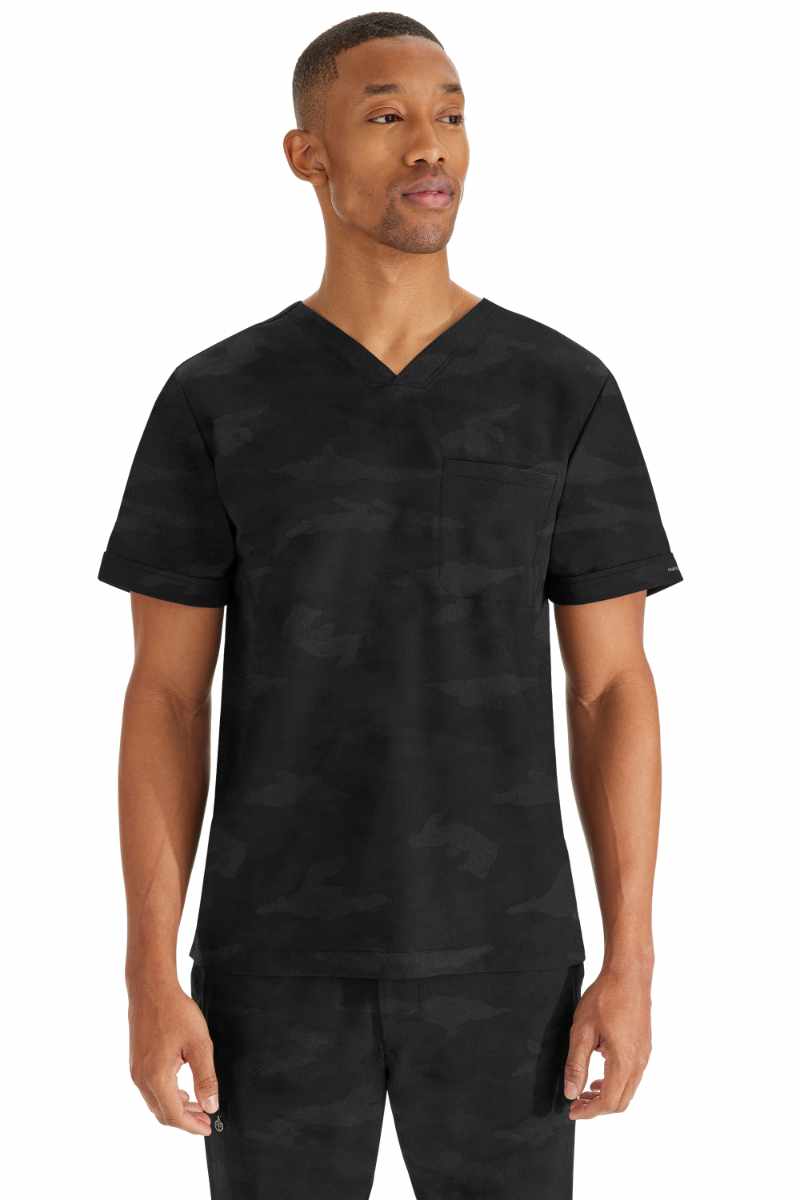 A young male Nursing Assistant wearing a Purple Label by Healing Hands Men's Jack Camo Scrub Top in "Black" size medium featuring 1 chest pocket on the wearer's left side.