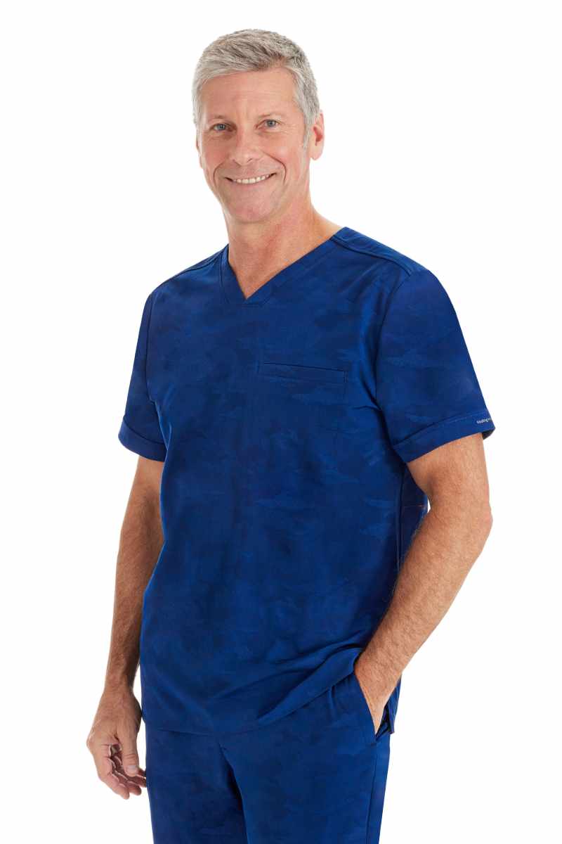 A male Medical Assistant wearing a Purple Label by Healing Hands Men's Jack Camo Scrub Top in "Navy" size XL featuring a modern fit.