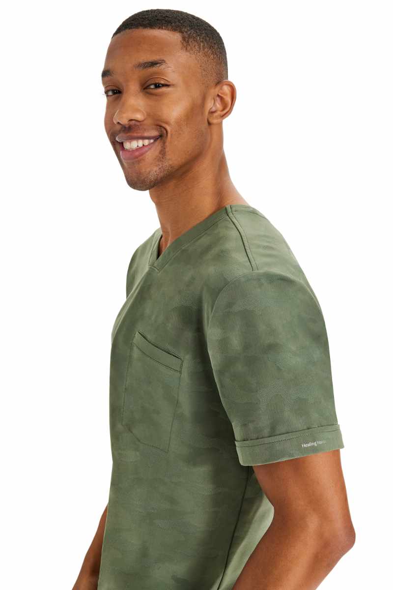 A young male Physical Therapist wearing a Purple Label by Healing Hands Men's Jack Camo Top in "Olive" size 2XL featuring folded cuffs at the sleeves.