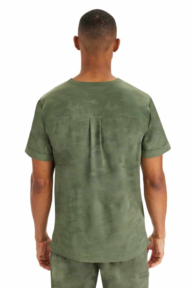 An image of a young male Dental Assistant Home Health Aide wearing a Purple Label by Healing Hands Men's Jack Camo Scrub Top in "Olive" size Large featuring a center back yoke with box pleat detail.
