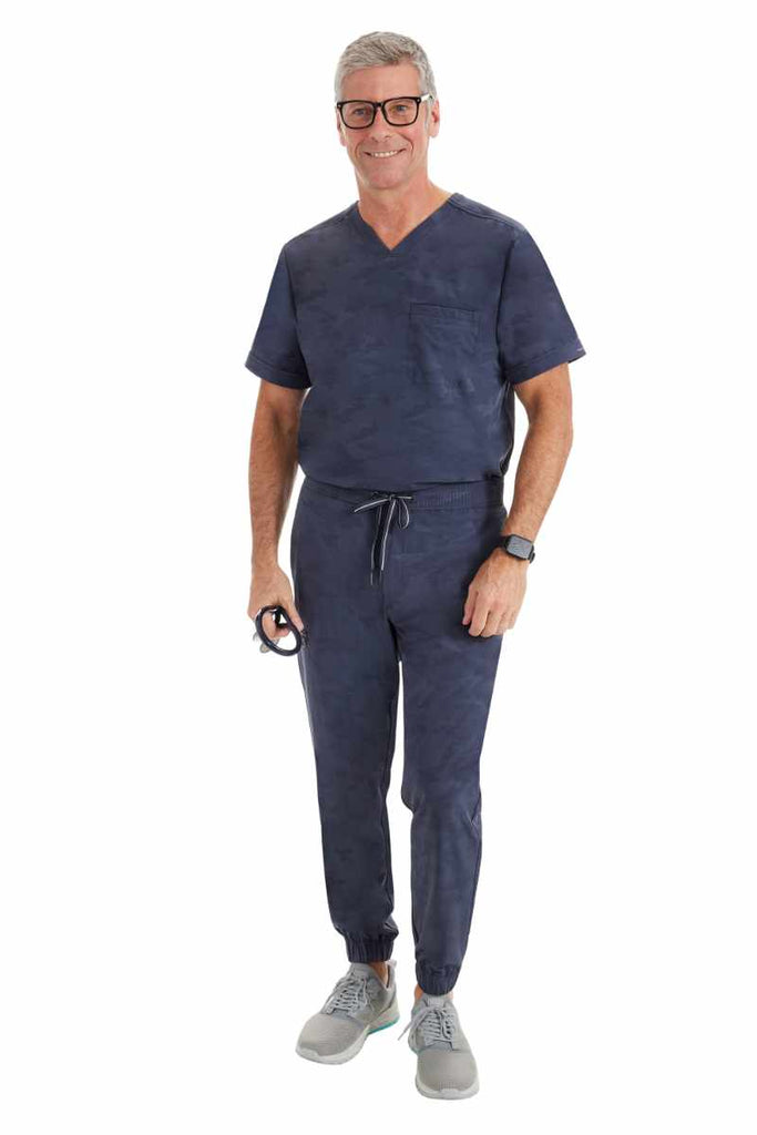 A male LPN wearing a Purple Label Men's Jack Camo Scrub Top & the matching Men's Drew Camo Jogger in Pewter.