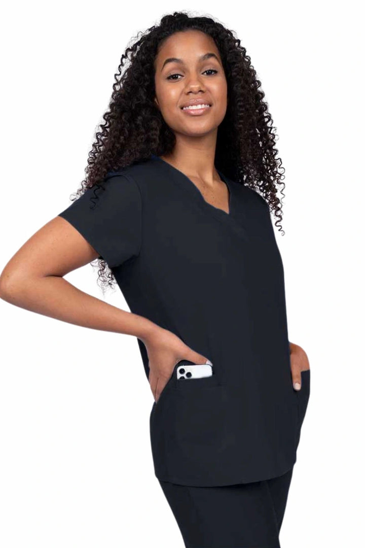 Young nurse wearing a Luv Scrubs by MedWorks Women's V-neck Scrub Top in black with featuring short sleeves, and a total of 3 pockets.