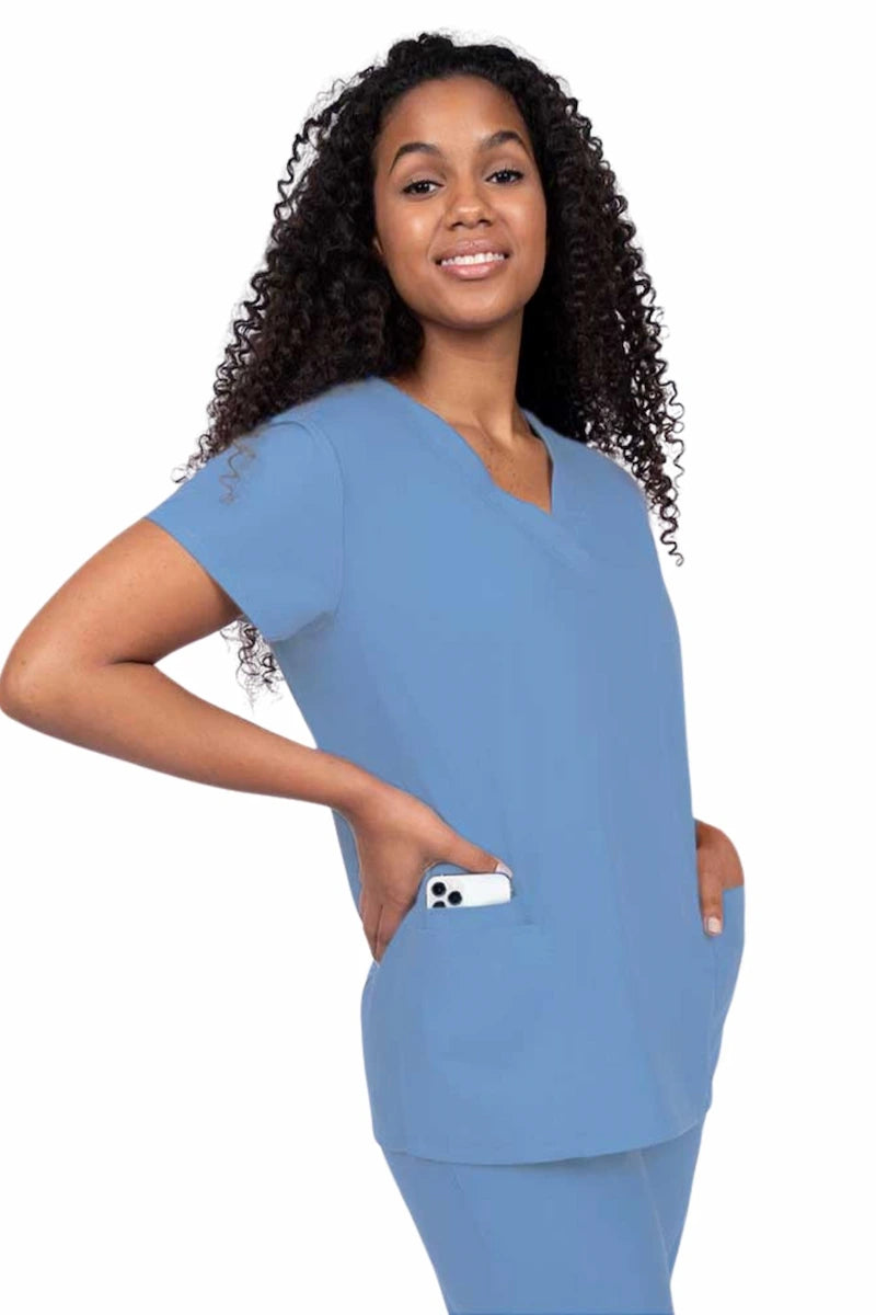 Young nurse wearing a Luv Scrubs by MedWorks Women's V-neck Scrub Top in ceil with featuring short sleeves, and a total of 3 pockets.