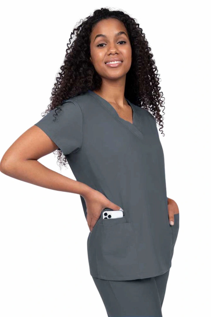 Young nurse wearing a Luv Scrubs by MedWorks Women's V-neck Scrub Top in pewter with featuring short sleeves, and a total of 3 pockets.