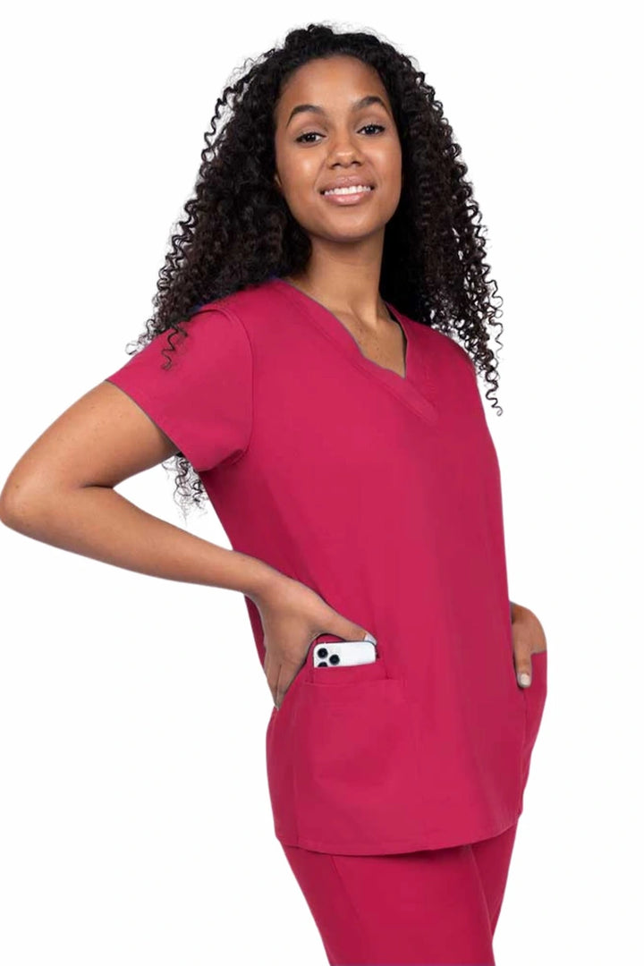 Young nurse wearing a Luv Scrubs by MedWorks Women's V-neck Scrub Top in red with featuring short sleeves, and a total of 3 pockets.