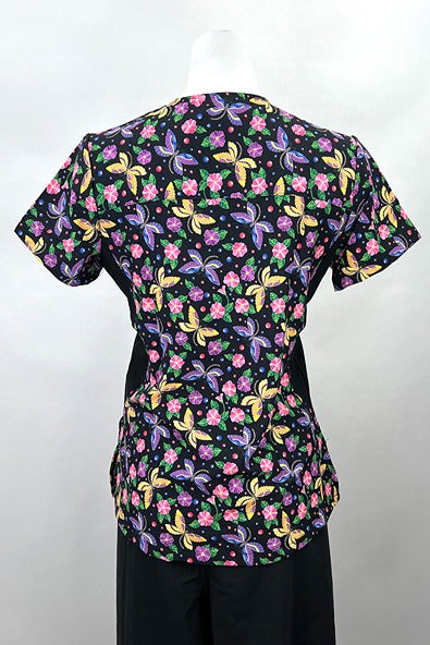 An image of the back of the Revel Women's Mock Wrap Print Scrub Top in "Floral Butterfly" size 3XL featuring a back yoke for shaping & side slits for additional range of motion.