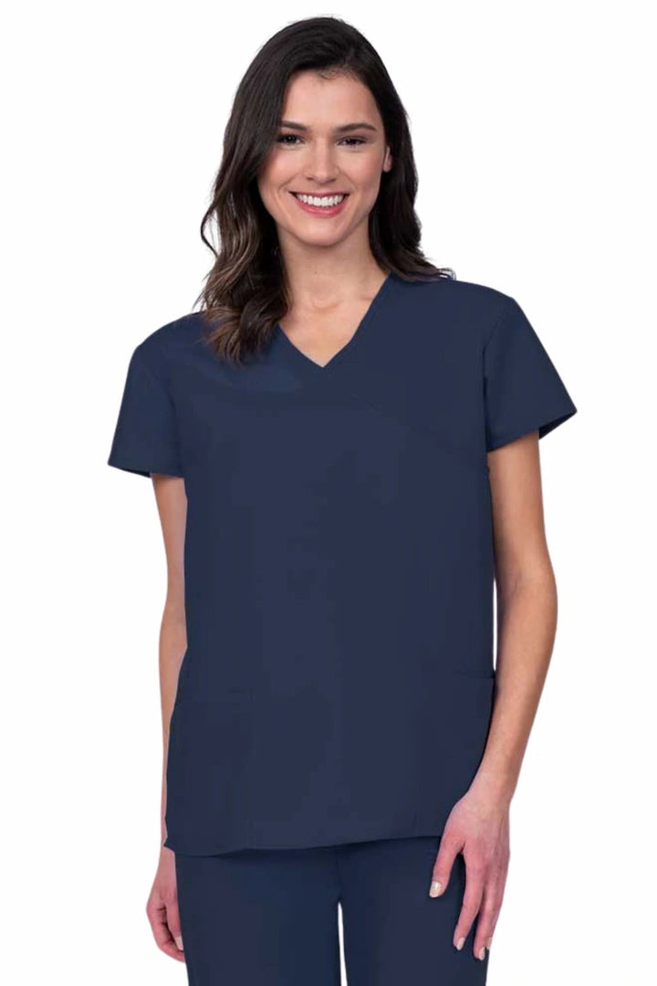 Young woman wearing a Luv Scrubs by MedWorks Women's Mock Wrap Scrub Top in navy featuring a Y-neckline and side slits for additional range of motion.