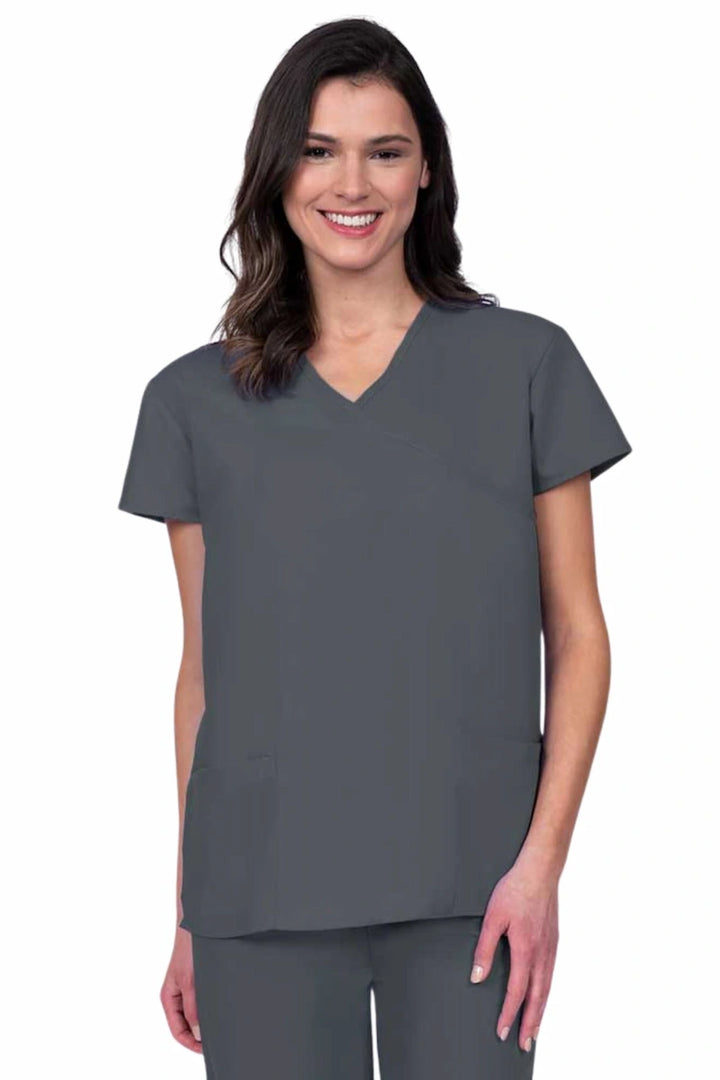 Young woman wearing a Luv Scrubs by MedWorks Women's Mock Wrap Scrub Top in pewter featuring a Y-neckline and side slits for additional range of motion.