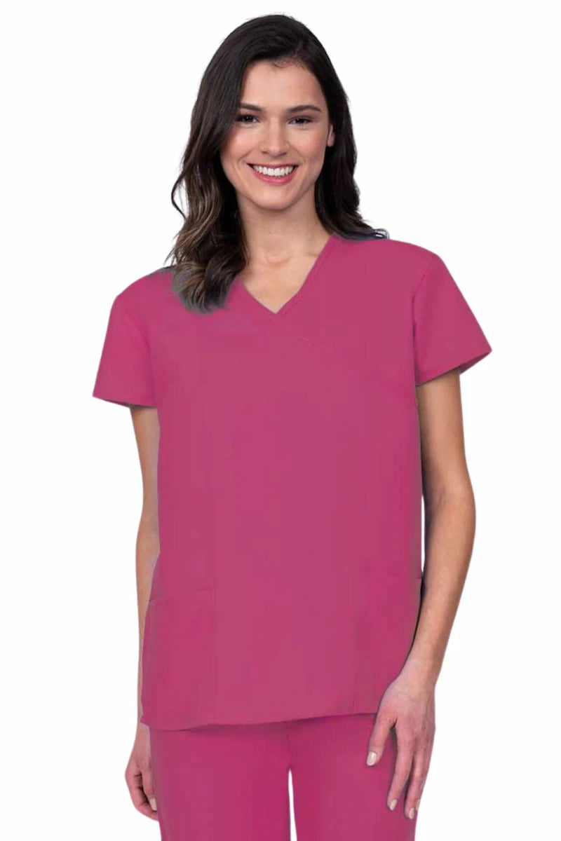 Young woman wearing a Luv Scrubs by MedWorks Women's Mock Wrap Scrub Top in shocking pink featuring a Y-neckline and side slits for additional range of motion.