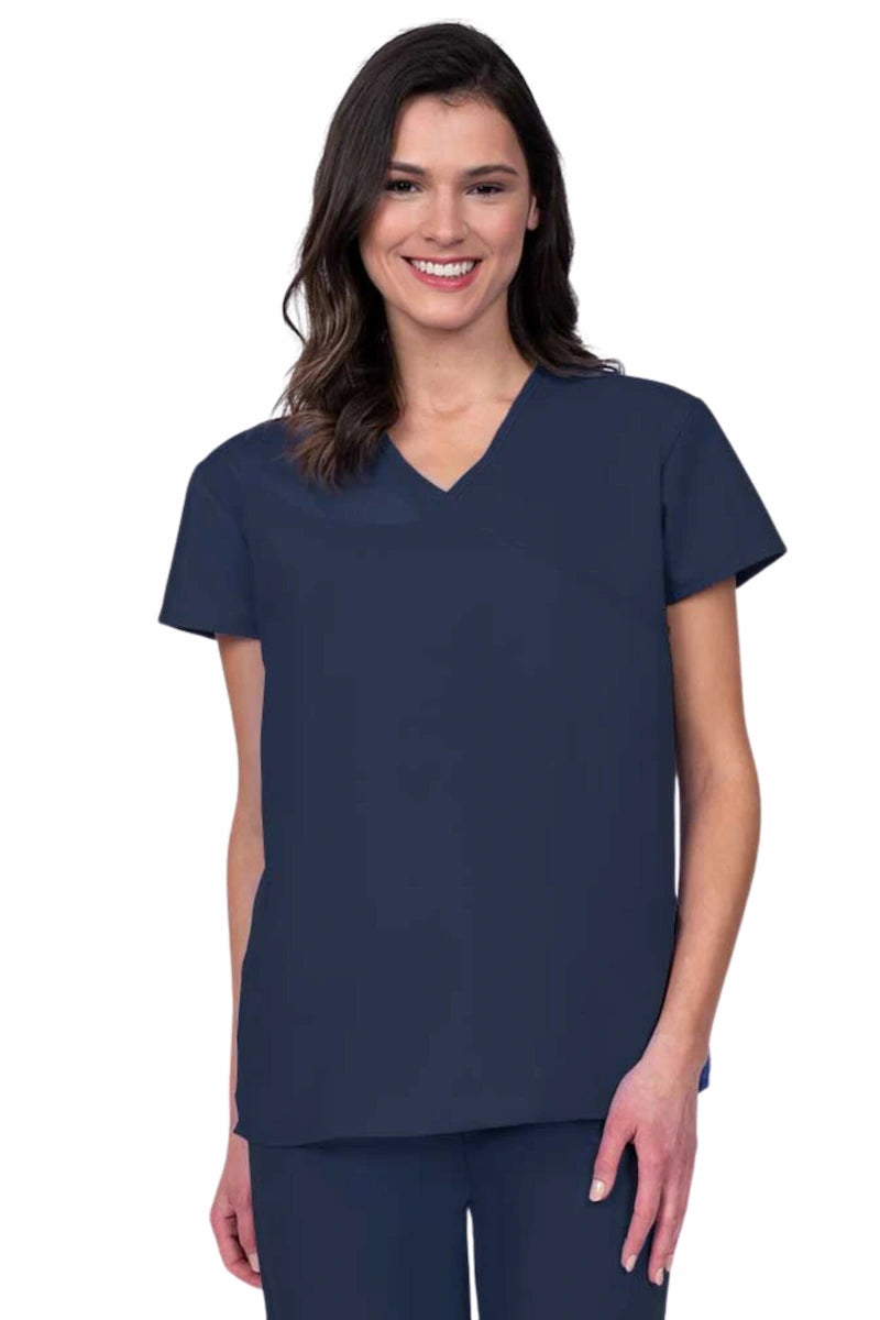 Nurse wearing a Luv Scrubs by MedWorks Women's Pocketless Mock Wrap Scrub Top in navy featuring a Y-neckline & side slits for additional mobility.