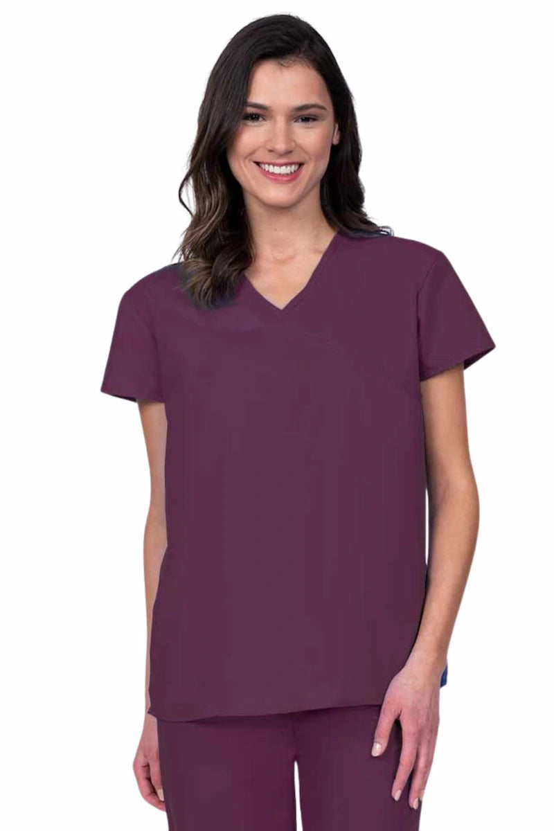 Nurse wearing a Luv Scrubs by MedWorks Women's Pocketless Mock Wrap Scrub Top in wine featuring a Y-neckline & side slits for additional mobility.