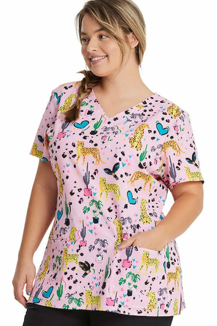 A young female Pediatric Nurse wearing a HeartSoul Women's V-Neck Print Scrub Top in Jungle of Love featuring two roomy front patch pockets.