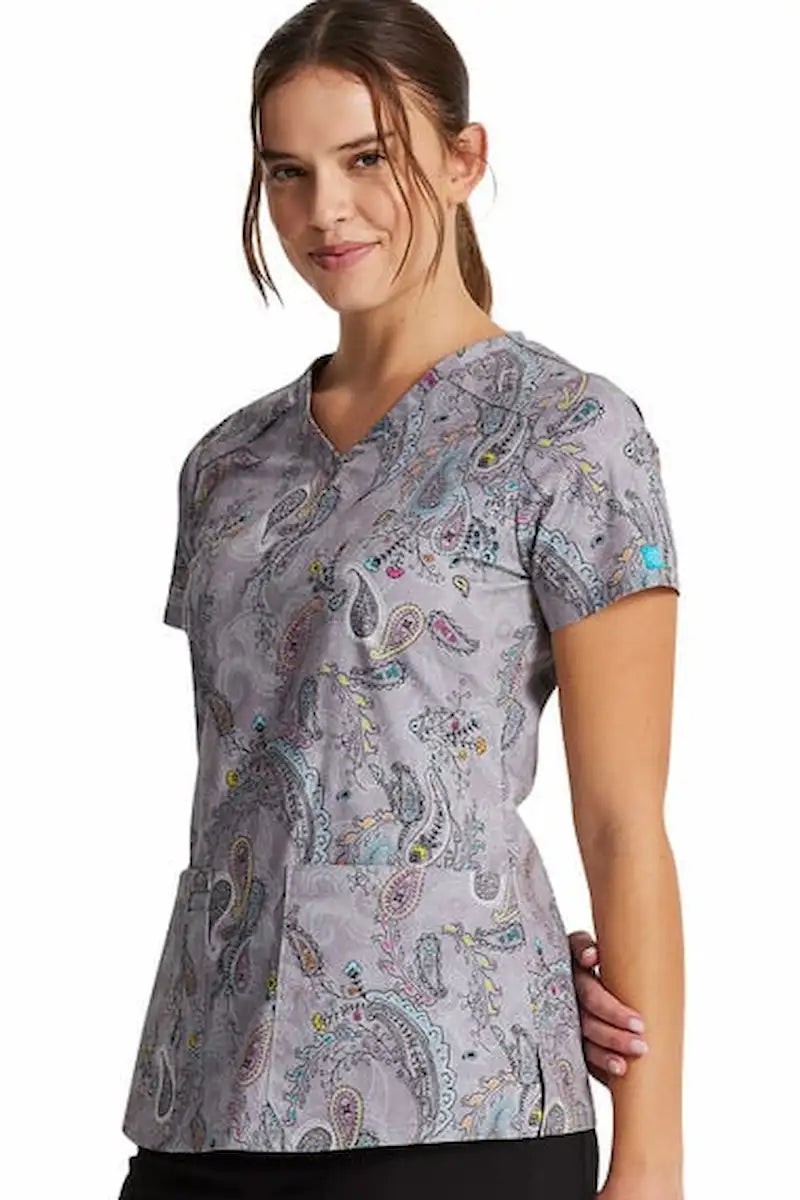 A young female Nurse wearing a Dickies Women's V-Neck Print Scrub Top in Denim Paisley featuring short sleeves.