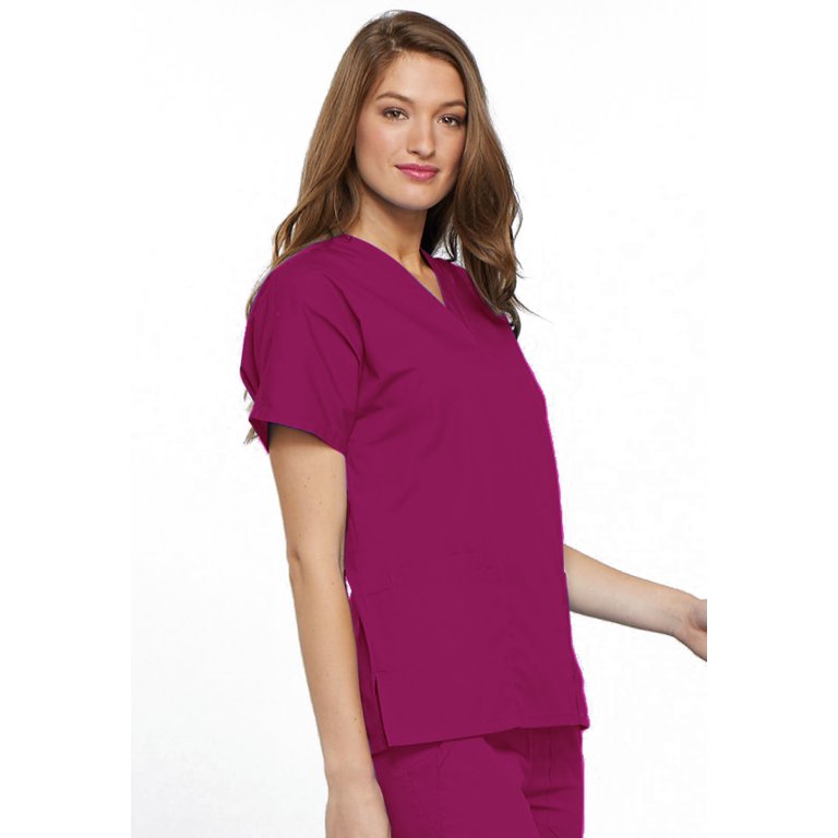 A young female Nurse wearing a Women's Multi-pocketed Scrub Top from Cherokee Workwear Originals in Raspberry featuring a side slits for additional range of motion.