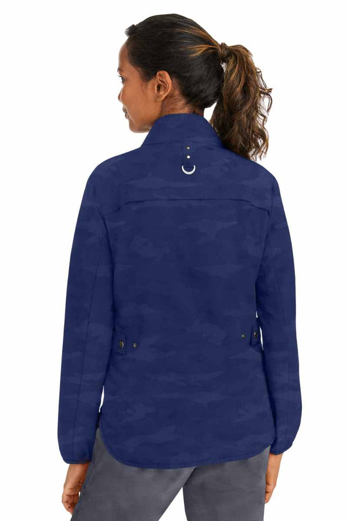 A young female Physical Therapist wearing a Purple Label Women's Destini Camo Scrub Jacket in Navy size 2XL featuring adjustable back tabs to ensure a flattering all day fit.