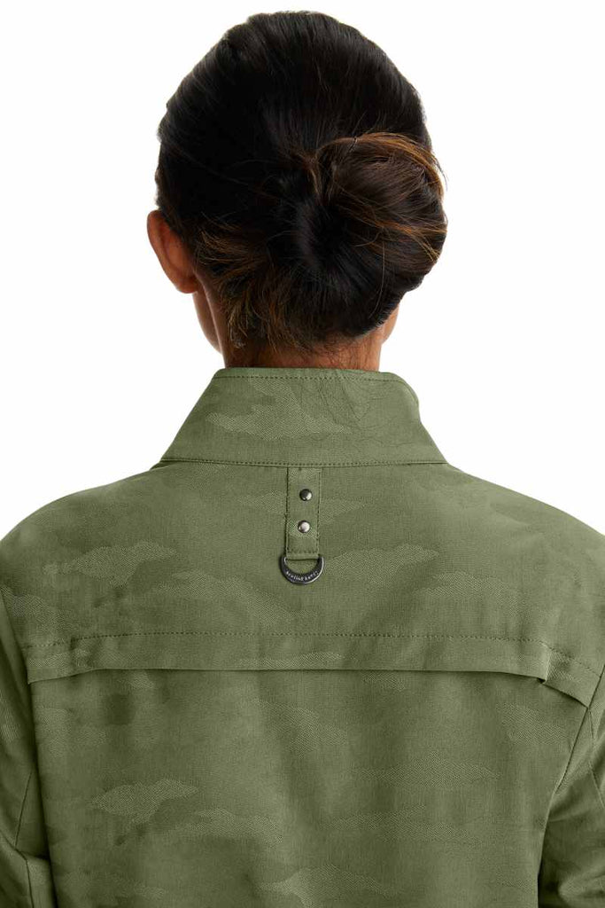 A young female Physician wearing a Purple Label Women's Destini Camo Scrub Jacket in Olive size XL featuring a center back yoke to ensure a flettering fit.