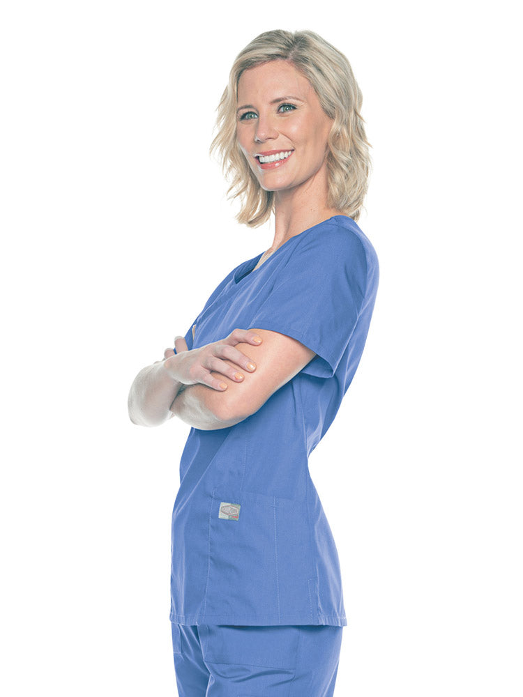 A young female Nursing Assistant wearing a Landau Women's Mock Wrap Scrub Top in Ceil size Medium featuring short sleeves.