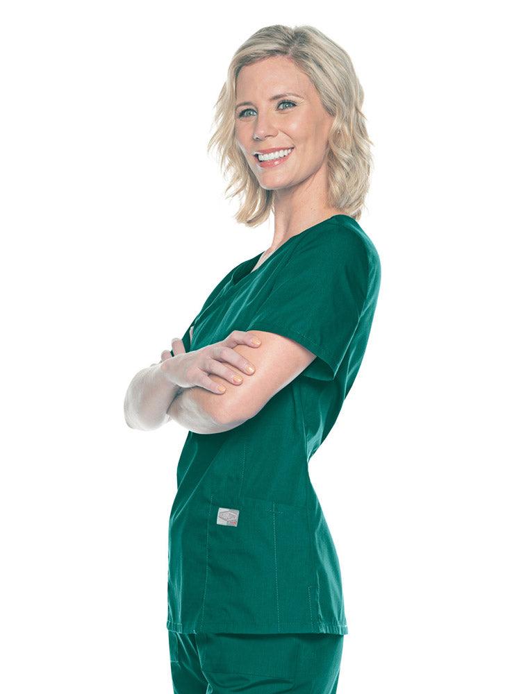 A young female Nursing Assistant wearing a Landau Women's Mock Wrap Scrub Top in Hunter Green size Medium featuring short sleeves.