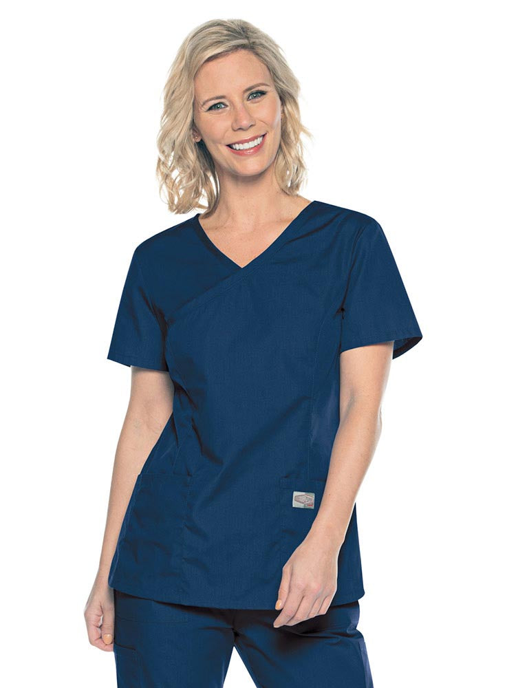 A young female Medical Assistant wearing a Landau ScrubZone Women's Mock Wrap Top in Navy size Small featuring a modern tailored fit.