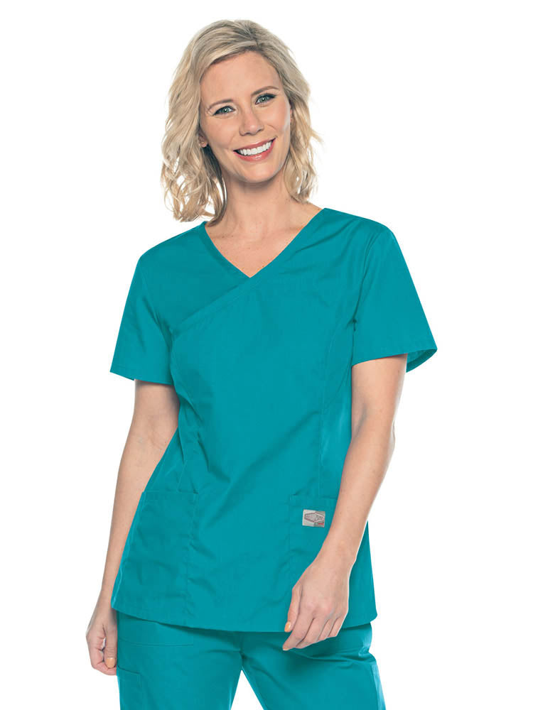 A young female Medical Assistant wearing a Landau ScrubZone Women's Mock Wrap Top in Teal size Small featuring a modern tailored fit.
