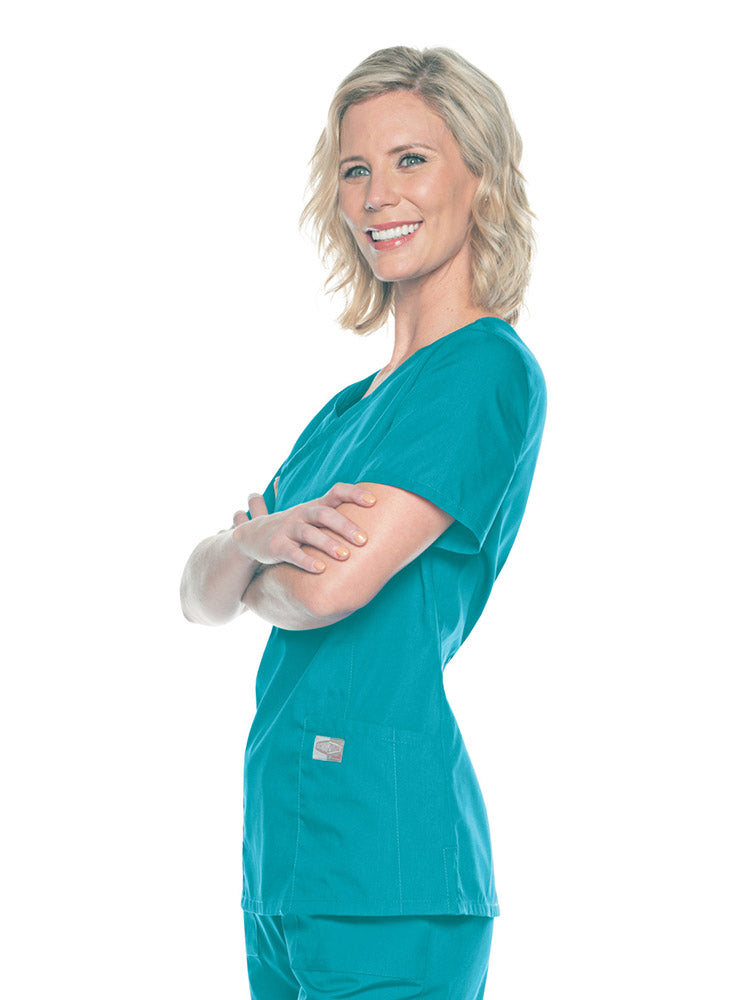 A young female Nursing Assistant wearing a Landau Women's Mock Wrap Scrub Top in Teal size Medium featuring short sleeves.