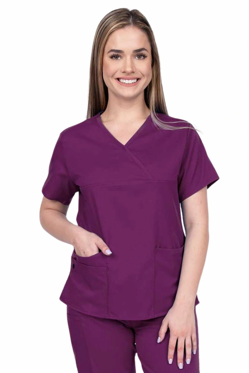 Young woman wearing an Epic by MedWorks Women's Y-Neck Scrub Top in eggplant with 2 front patch pockets.