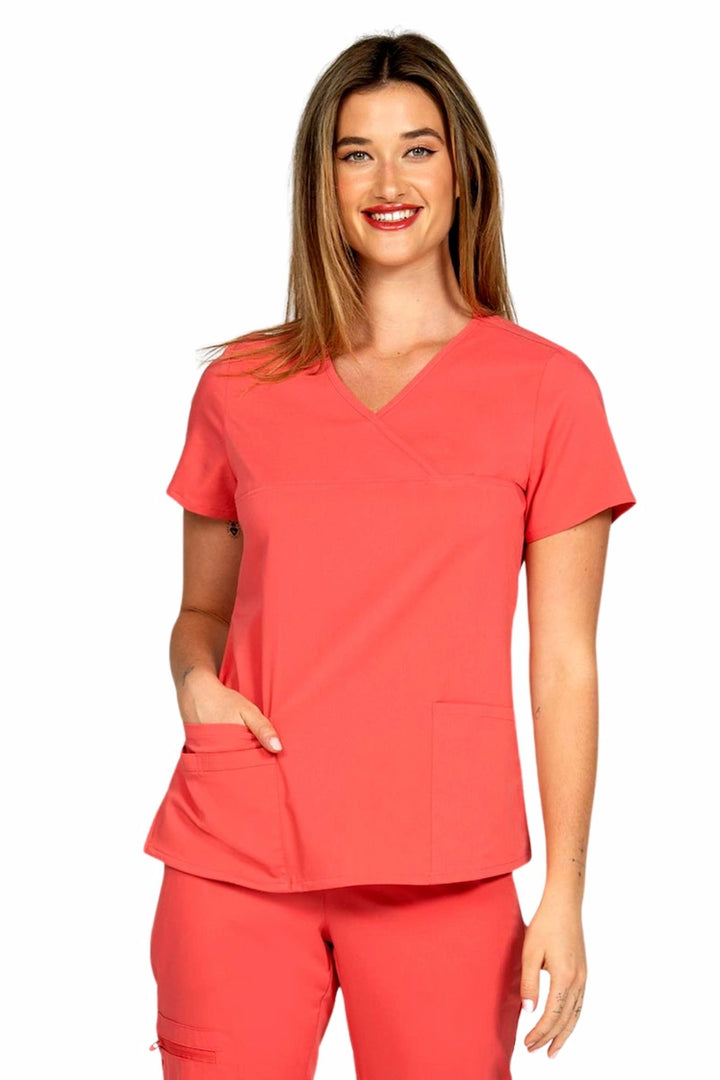 A young female LPN wearing an Epic by MedWorks Women's Y-Neck Scrub Top in Coral featuring a Y-neckline with short sleeves.