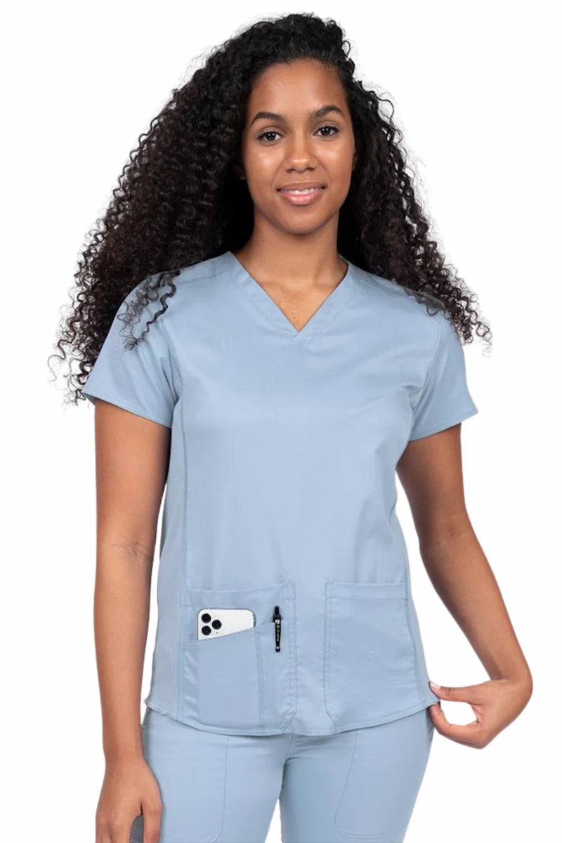 Nurse wearing an Epic by MedWorks Women's Blessed Scrub Top in blue fog with a V-neckline & short sleeves.