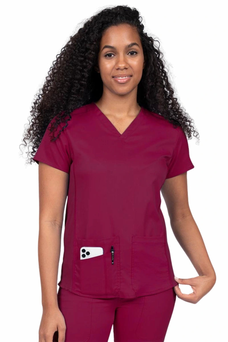 Nurse wearing an Epic by MedWorks Women's Blessed Scrub Top in wine with a V-neckline & short sleeves.