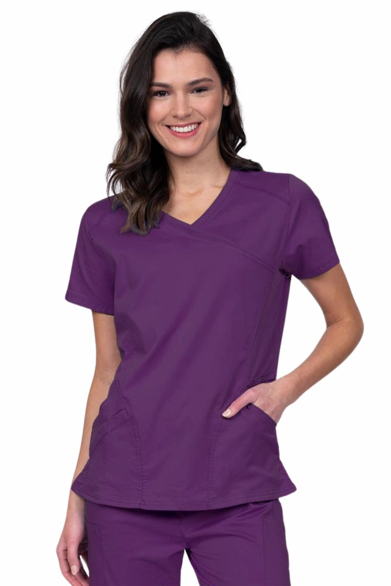 Young RN wearing an Epic by MedWorks Women's Knit Collar Mock Wrap Scrub Top in eggplant featuring a Y-neckline with short sleeves.