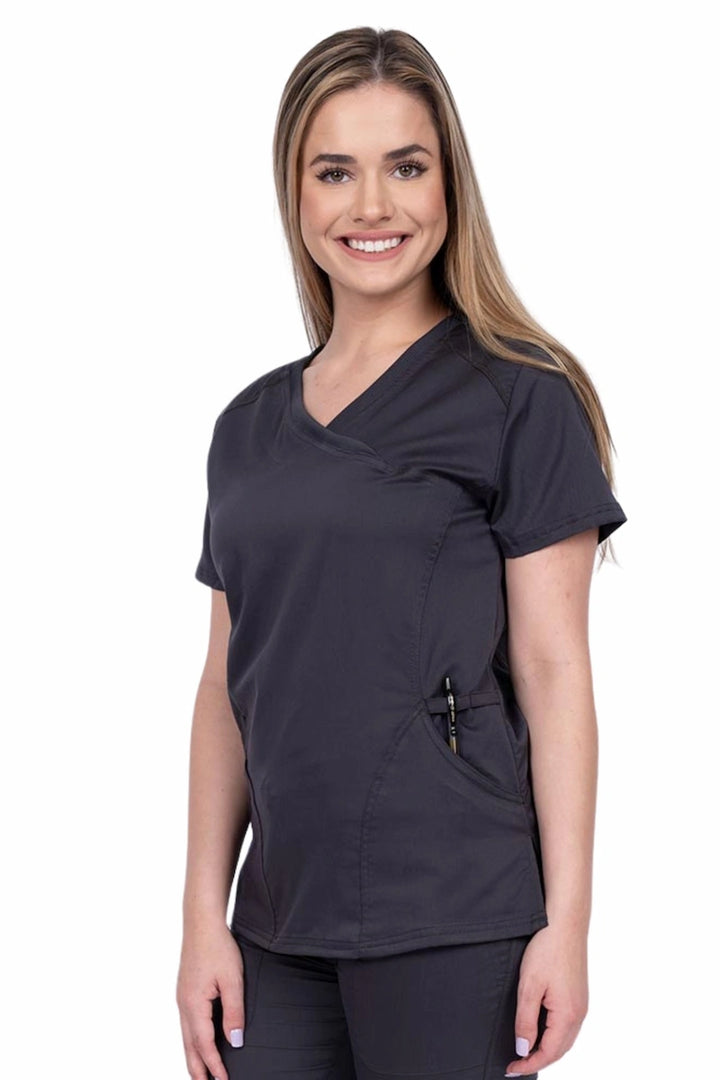 Young RN wearing an Epic by MedWorks Women's Knit Collar Mock Wrap Scrub Top in pewter featuring a Y-neckline with short sleeves.