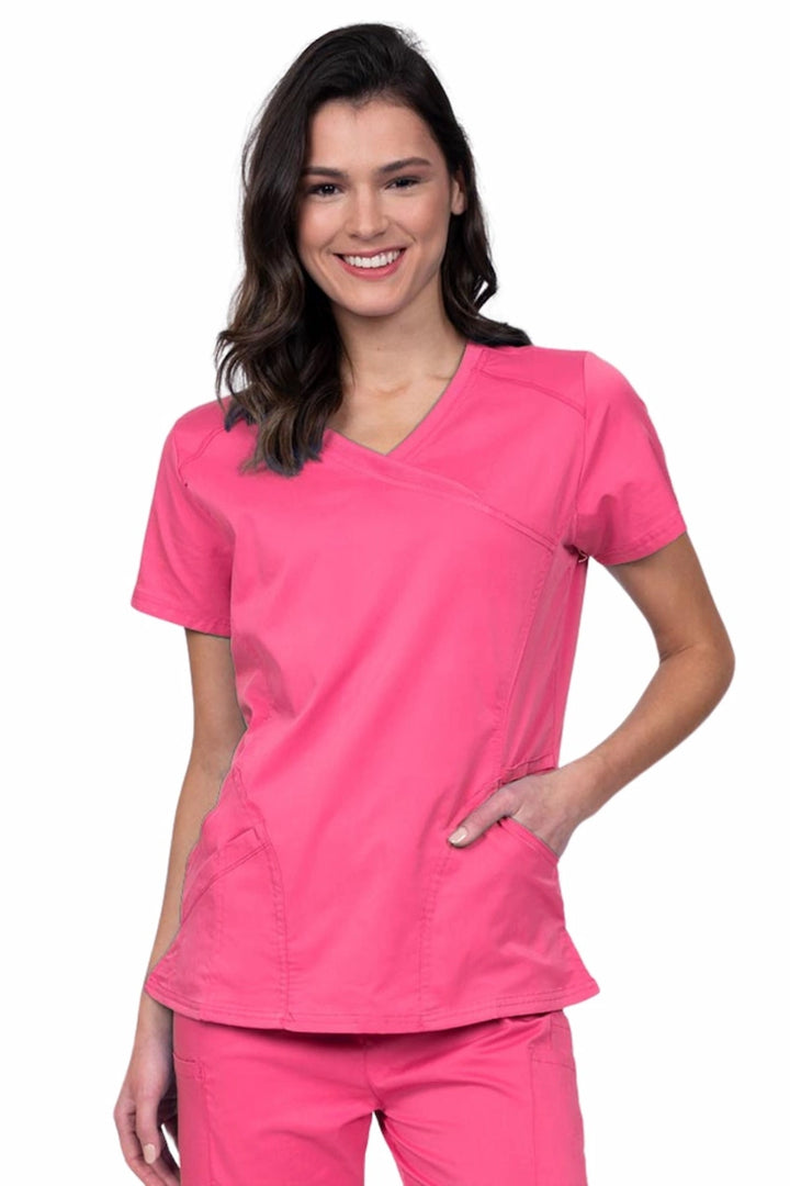 Young RN wearing an Epic by MedWorks Women's Knit Collar Mock Wrap Scrub Top in shocking pink featuring a Y-neckline with short sleeves.