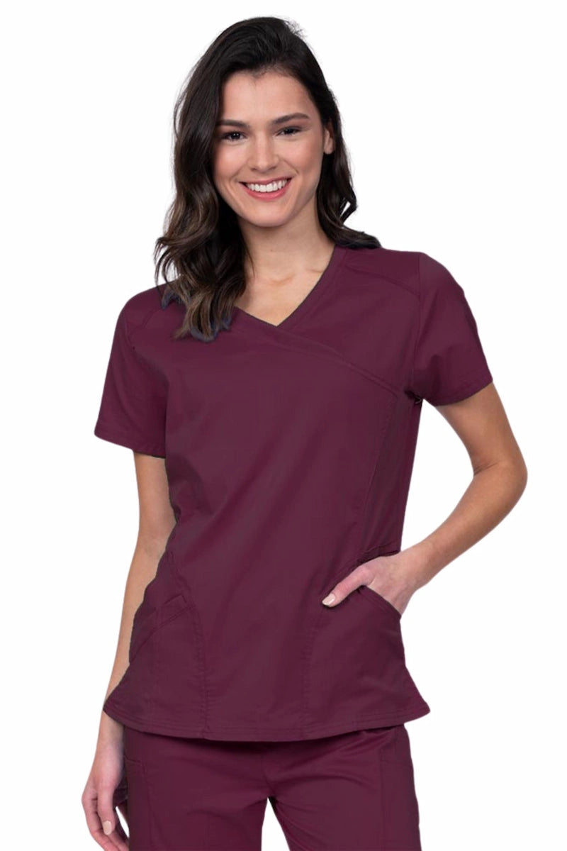 Young RN wearing an Epic by MedWorks Women's Knit Collar Mock Wrap Scrub Top in wine featuring a Y-neckline with short sleeves.