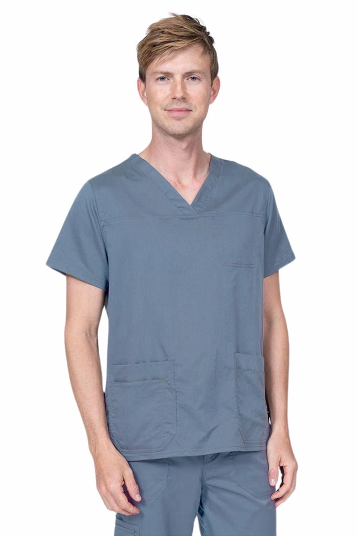 Male healthcare professional wearing an Epic by MedWorks Men's Scrub Top in blue fog with 2 front patch pockets and 1 exterior cell phone pocket on the wearer's right side.