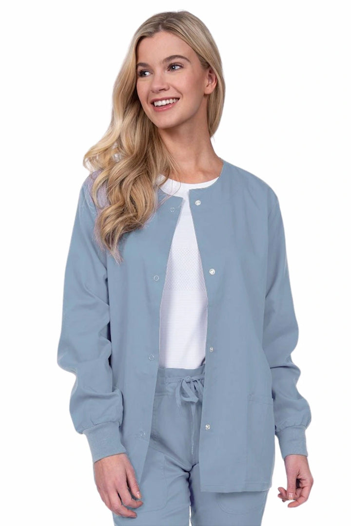 Young female healthcare worker wearing an Epic by MedWorks Women's Snap Front Scrub Jacket in blue fog with two front patch pockets.