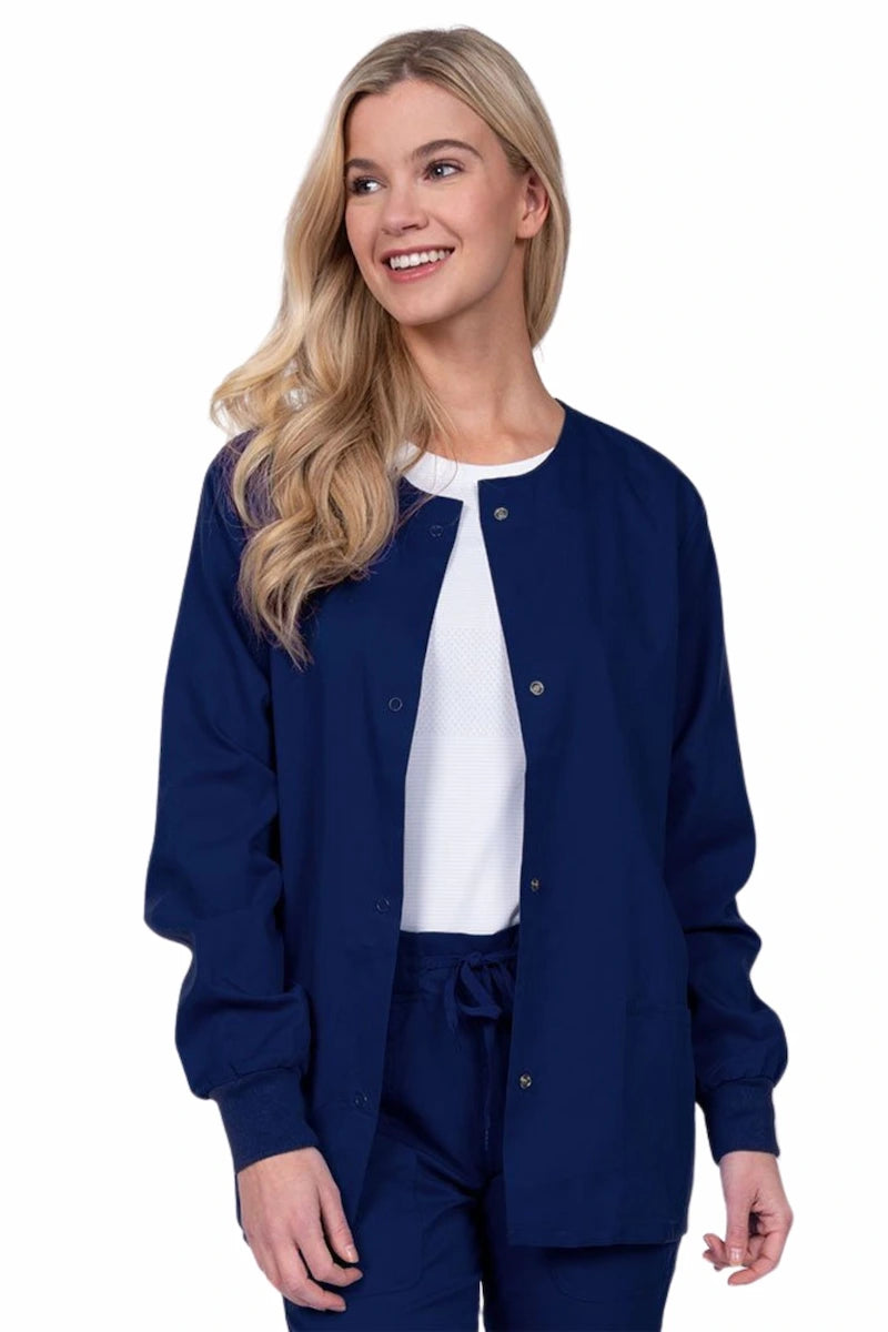 Young female healthcare worker wearing an Epic by MedWorks Women's Snap Front Scrub Jacket in navy with two front patch pockets.