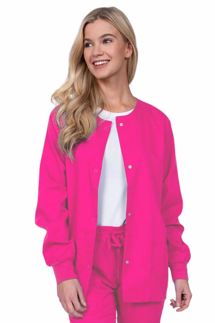 Young female healthcare worker wearing an Epic by MedWorks Women's Snap Front Scrub Jacket in shocking pink with two front patch pockets.